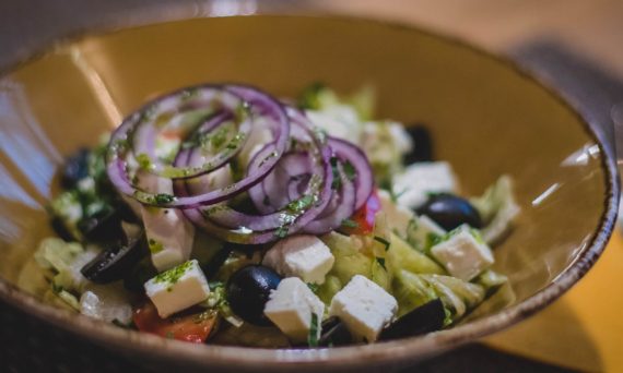 A mouth-watering Greek salad featuring fresh feta, black olives, and red onion rings.
